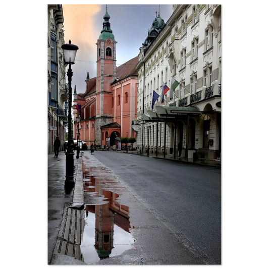 Photo par Kellestom. Cathédrale rose de Ljubljana reflétée dans une flaque d’eau sur une rue mouillée en Slovénie