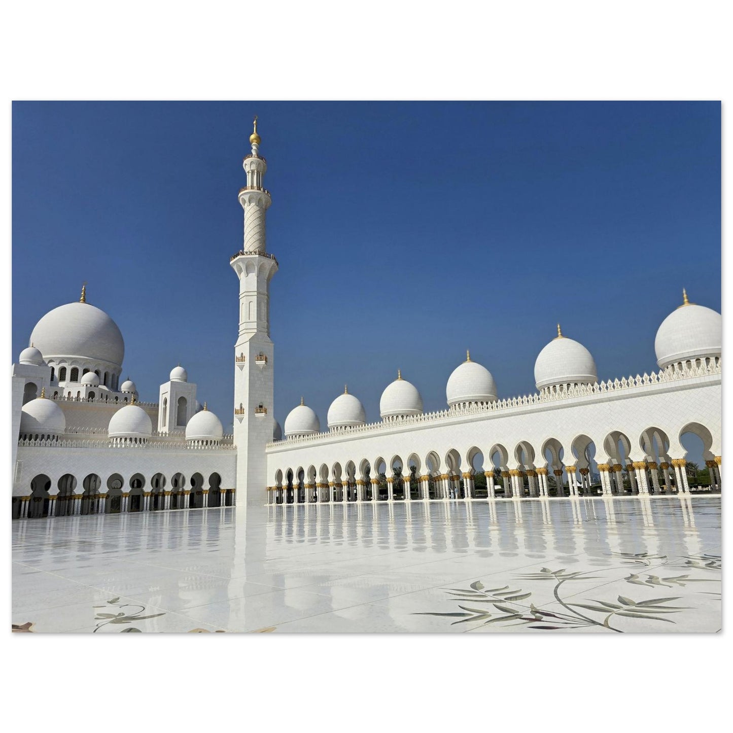 Photo de vue perspective de la Grande Mosquée d'Abu Dhabi avec ses dômes blancs et sa cour en marbre poli.