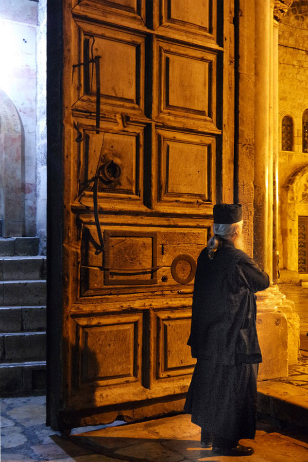 Photographie d'art 20x30cm de Jérusalem montrant une immense porte ancienne éclairée de nuit avec une silhouette solitaire dans une ambiance spirituelle.