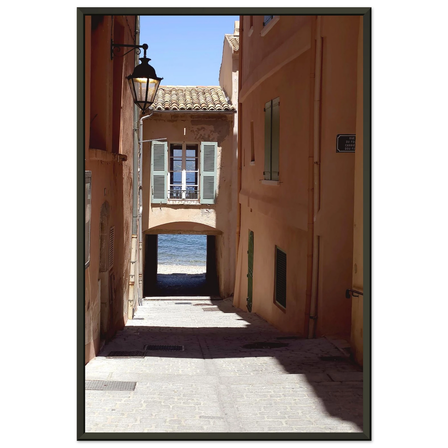 Photo d'art d'une ruelle ombragée à Saint-Tropez menant vers la mer Méditerranée avec architecture provençale