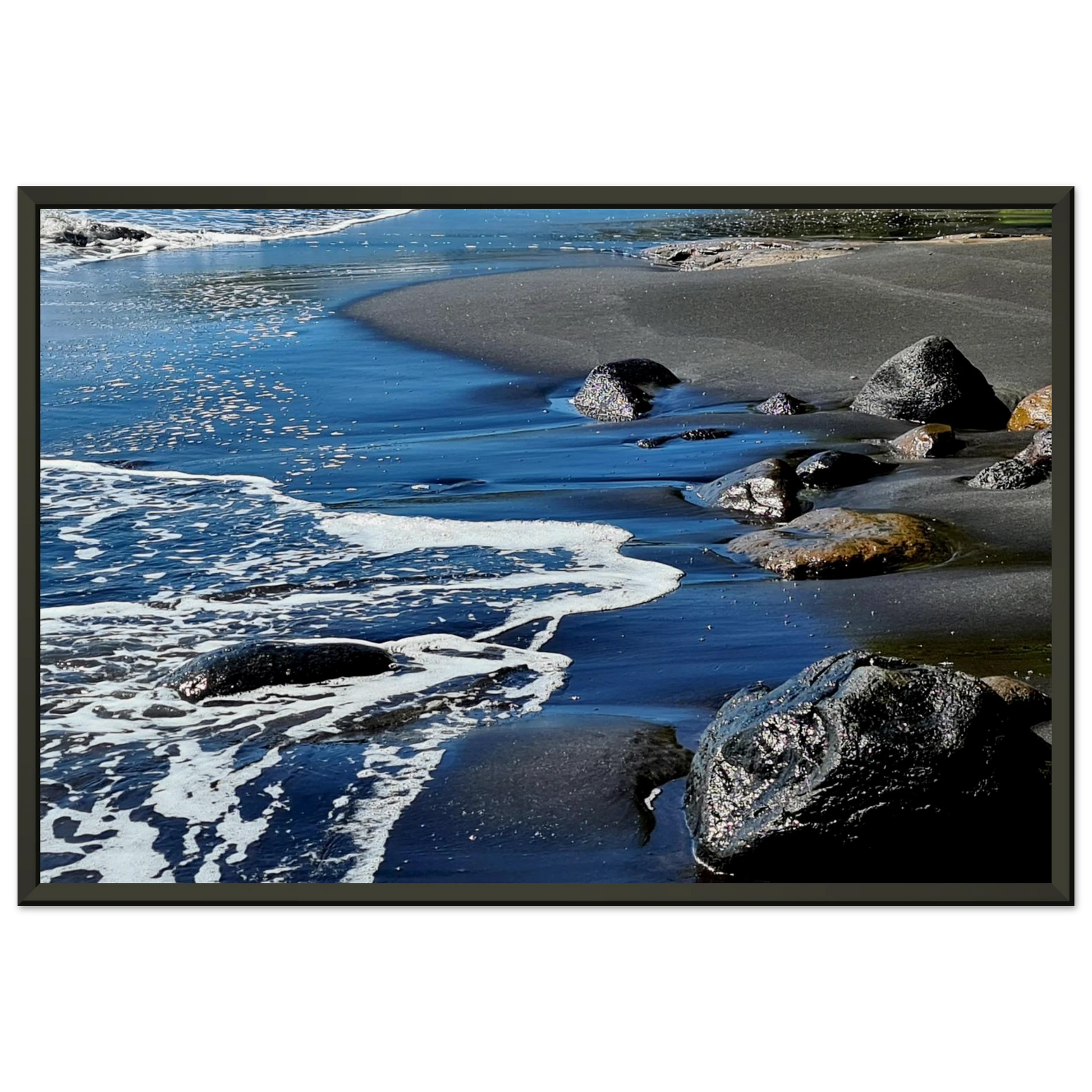 Photographie d'art d'une plage de sable noir volcanique avec écume de mer blanche et rochers humides, format 30x45 cm | Kellestom