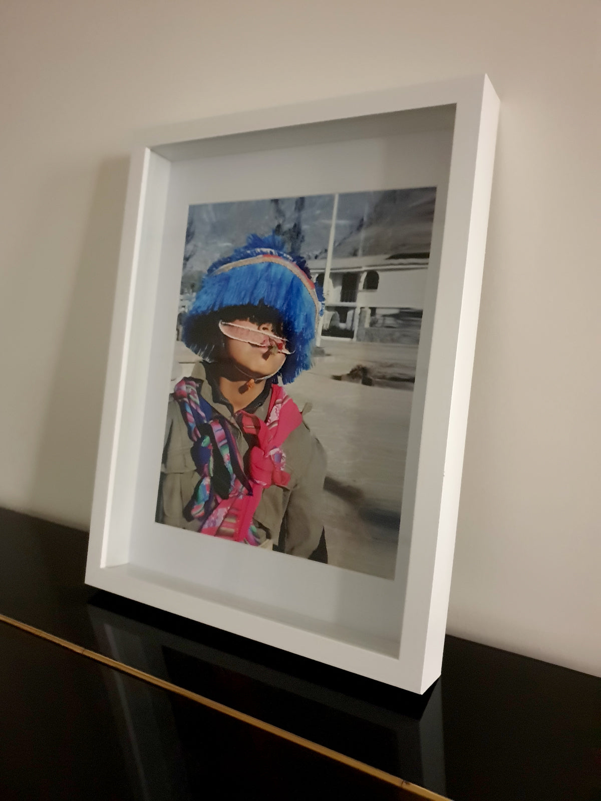 Portrait rapproché d'un jeune garçon péruvien portant un grand chapeau traditionnel en laine bleu vif à franges et des écharpes colorées à motifs andins.